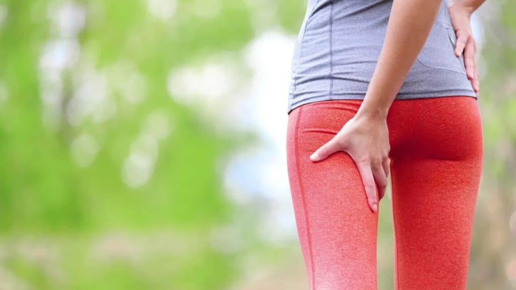femme en legging de sport avec une douleur à l'ischio jambiers