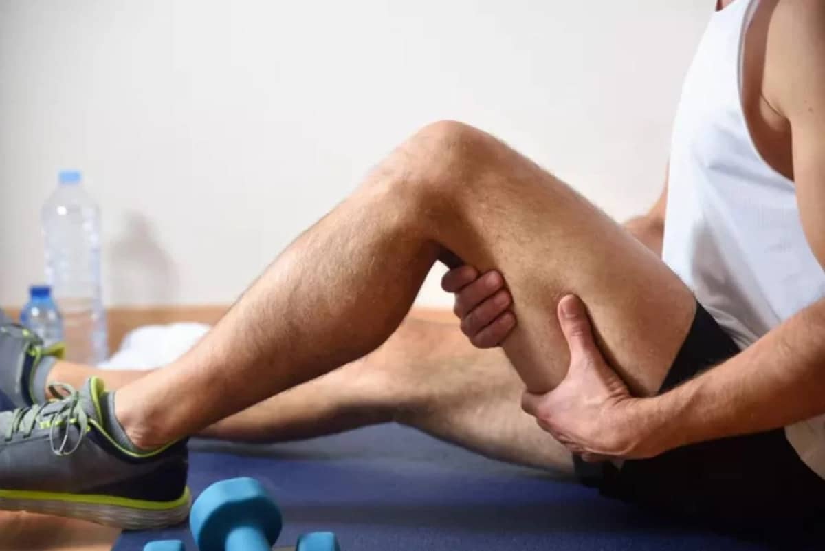 homme assis au sol en tenue de sport avec une douleur à l'ischio jambiers