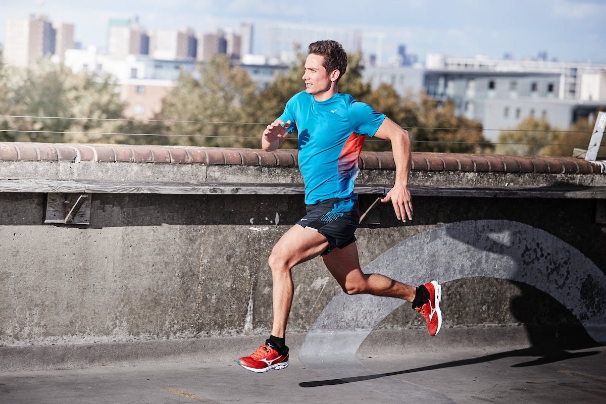 homme en bleu en course à pied le long d'un muret en ville