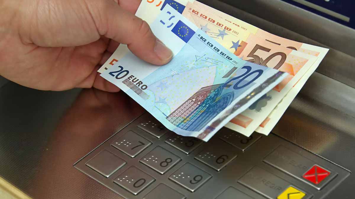 ditributeur à billets avec un homme avec des billets dans la main