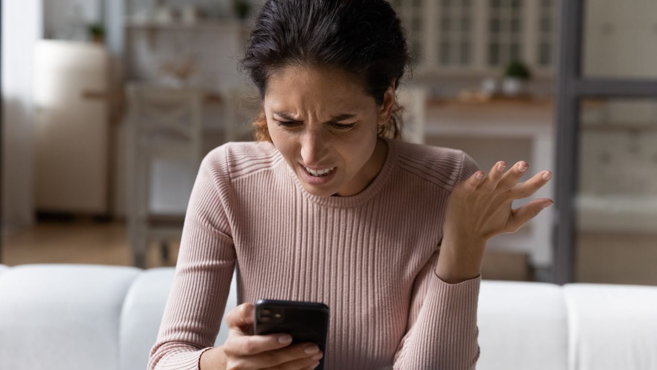 femme devant son téléphone énervé