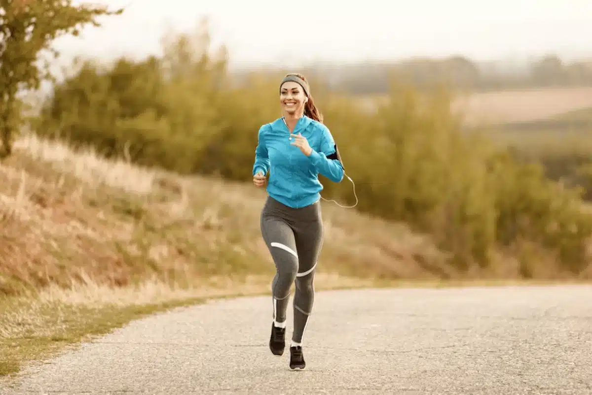 femme en course à pied dans la campagne sur la route avec des écouteurs
