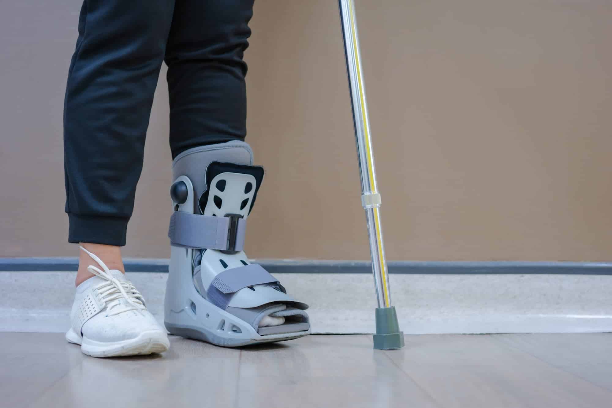 homme avec une botte de marche debout et une béquille