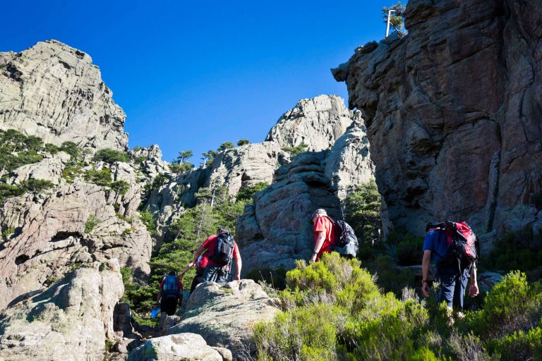 randonnée en corse avec des hommes sur un sentier entre les roches