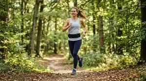 Femme qui court sur un sentier forestier entre les arbres