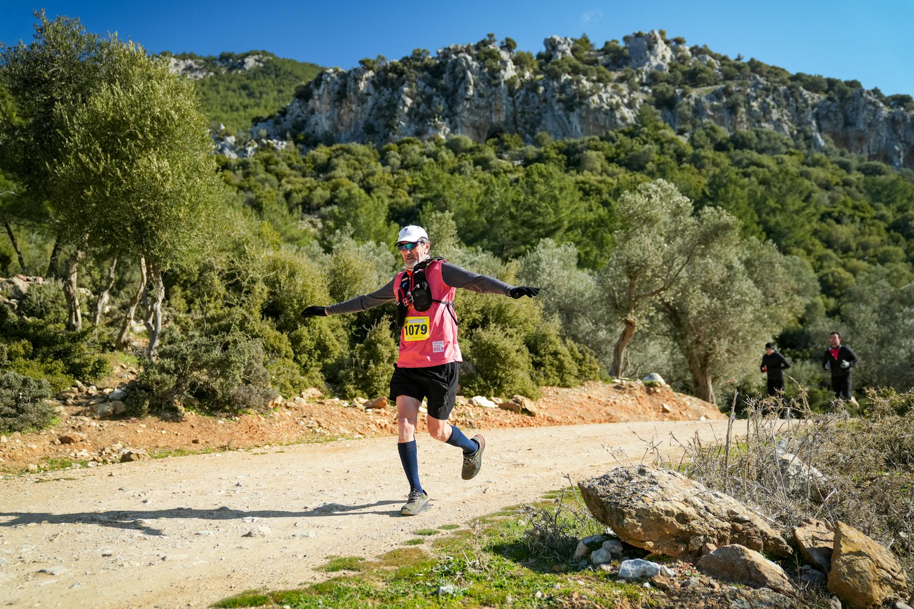 Coureur trail en montagne avec chaussettes techniques visibles sur terrain rocheux